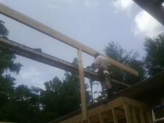 Carpenter setting a ridge beam over a new addition frame — Ice Dam Removal by Roofing Brothers in Badger