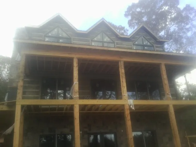Dormers and porch framing on a large log home under construction — Roof Coating work by our crew in Badger