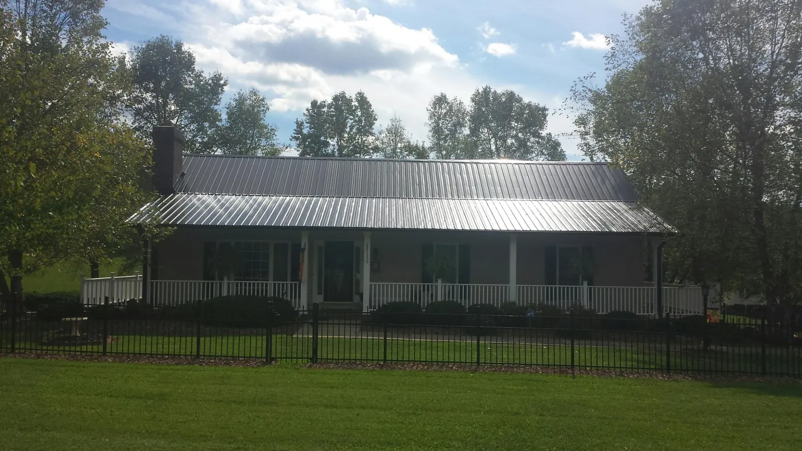 Gray metal roof on a brick ranch with a full width front porch — Gutter Guard Installation work by our crew in Badger