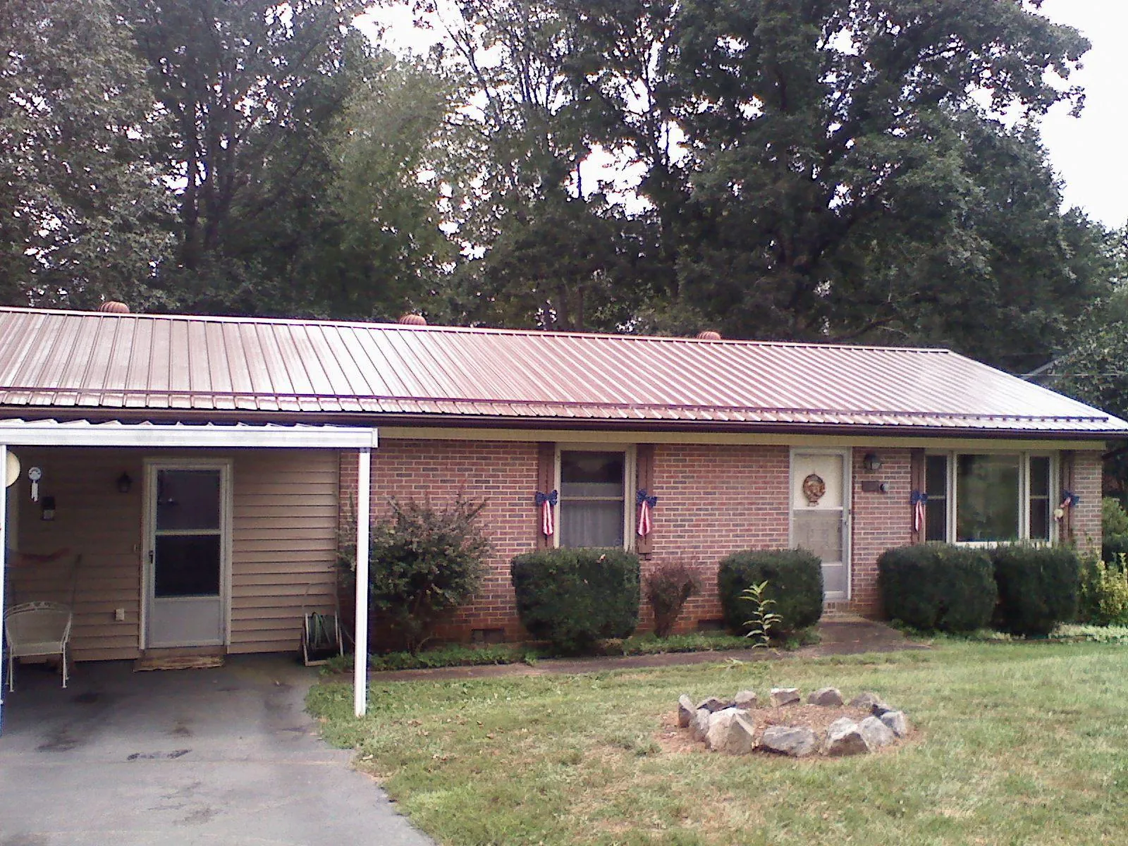 Bronze metal roof and carport on a brick ranch home — Roof Repair work by our crew in Badger